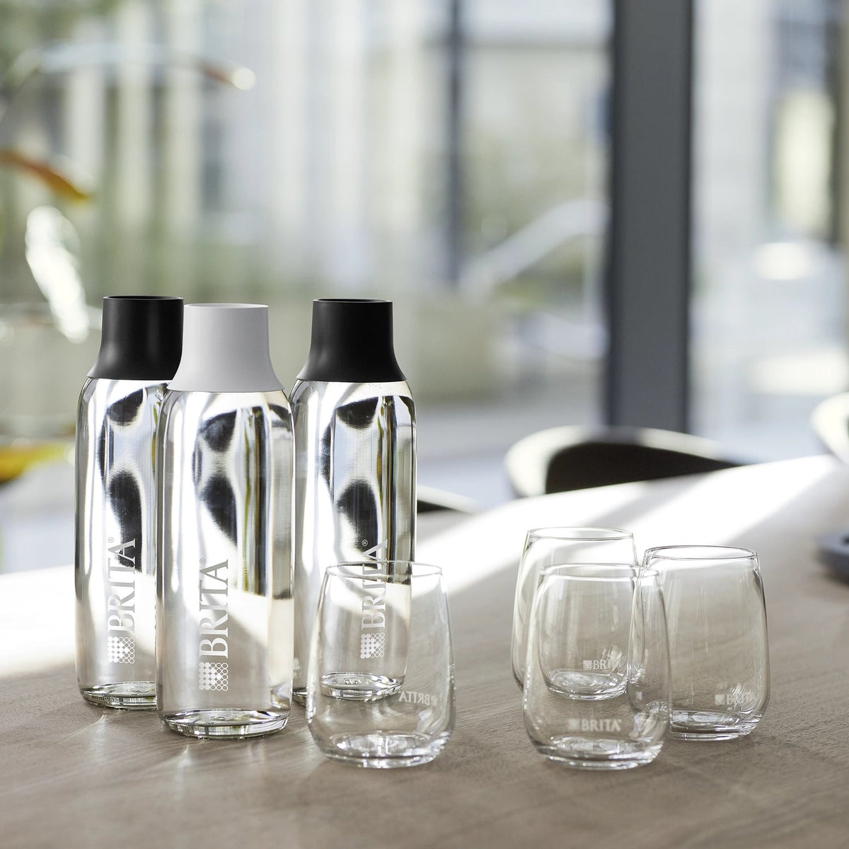 BRITA Wave bottles and glasses standing on a table with a blurred office background.