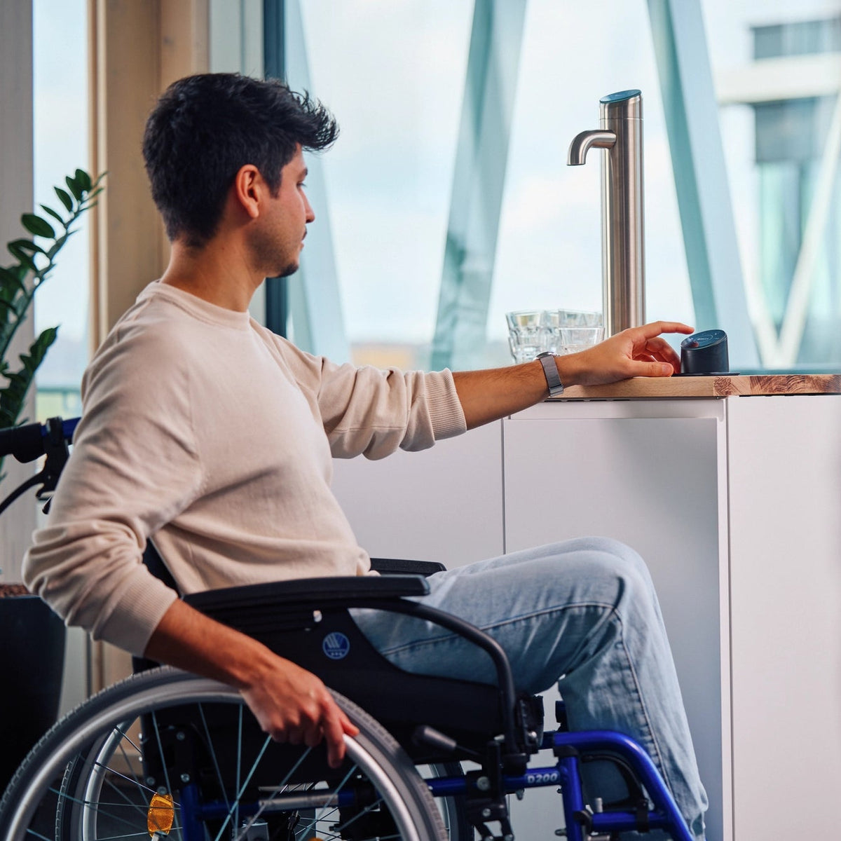 Man in a wheelchair dispensing water with a Easy Access Panel from a BRITA I-Tap.