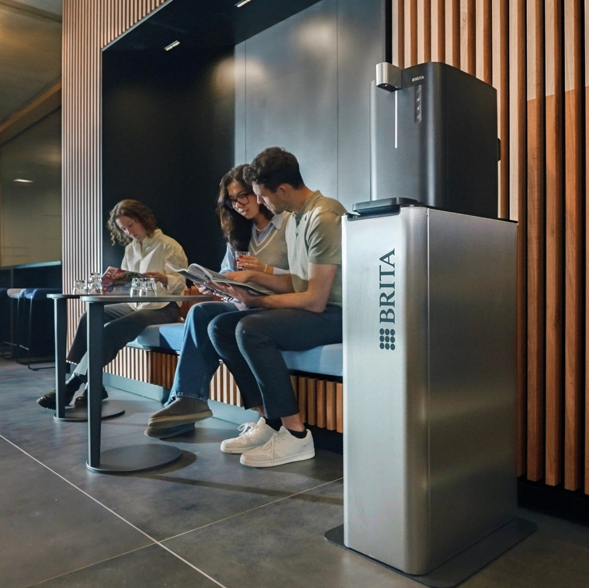 People sitting in a modern office setting next to a BRITA Top Compact Water Dispenser.