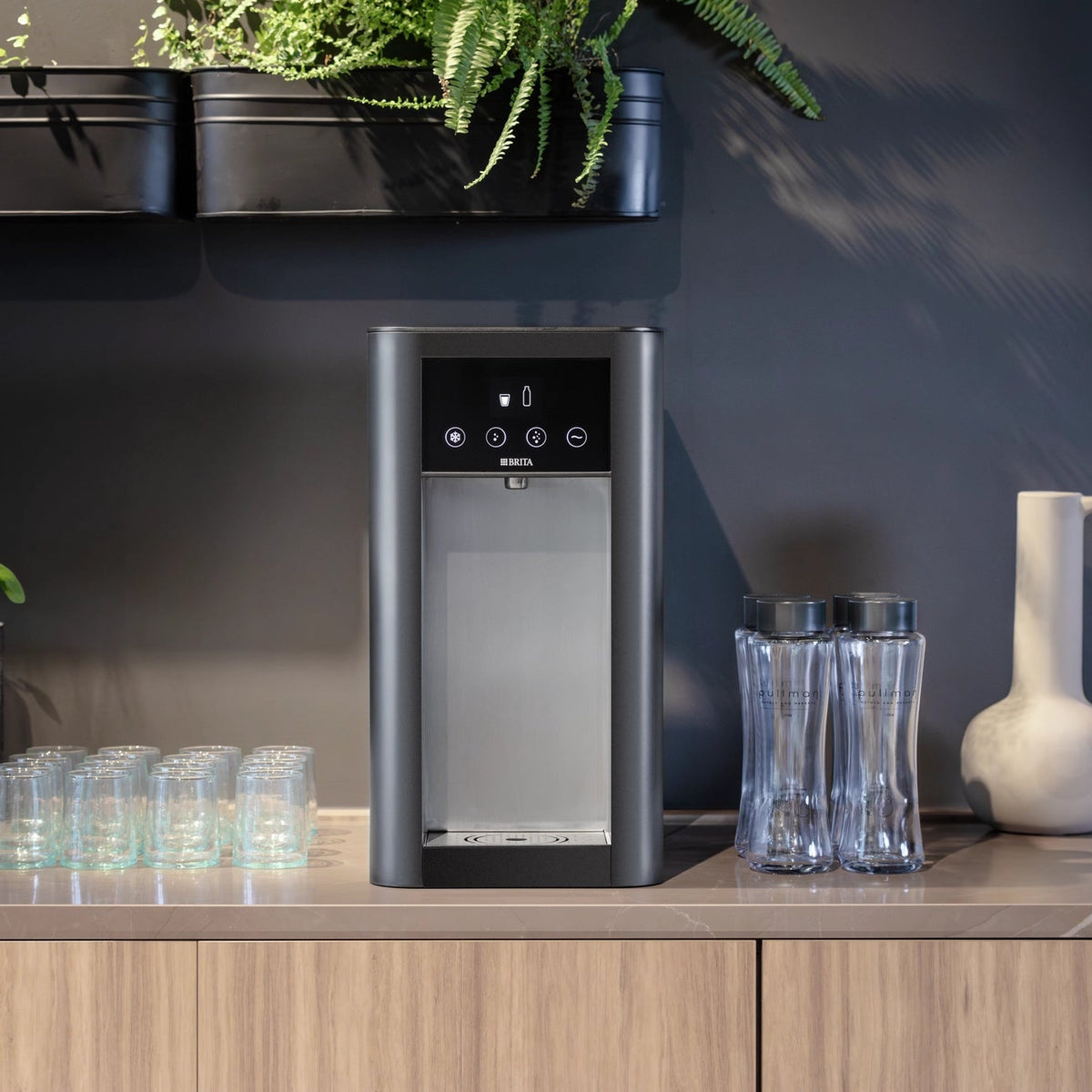 Top Pro water dispenser on a kitchen countertop with glasses and bottles in a modern kitchen setting.