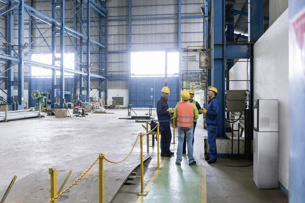 Workers in a factory setting with safety equipement standing next to a Top Pro.